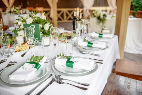 Table setting with sparkling wineglasses, plate with white napkin and cutlery on table, copy space. Place set at wedding reception. Table served for wedding banquet in restaurant