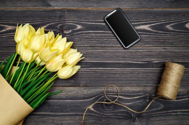 Koyu ahşap arka planda sarı lale çiçekleri, kopyalama alanı. Bahar minimum konsepti. Kadınlar Günü, Anneler Günü, Sevgililer Günü, Paskalya, doğum günü. Düz yatış, üst görünüm