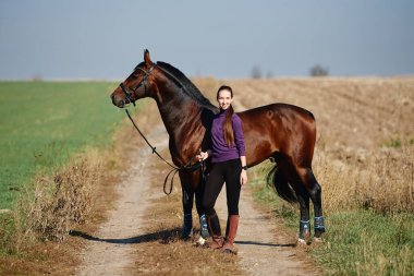 Yaz günü çiftlikte atla ilgilenen genç bir kadın çiftçi, fotokopi odası. Kız ve kahverengi at açık havada