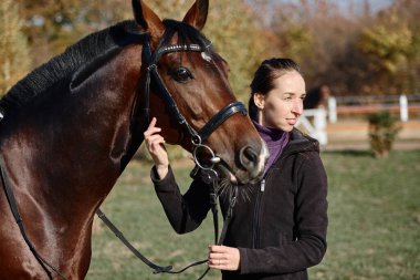 Yaz günü çiftlikte atla ilgilenen genç bir kadın çiftçi, fotokopi odası. Kız ve kahverengi at açık havada