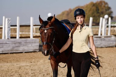 Yaz günü çiftlikte atla ilgilenen genç bir kadın çiftçi, fotokopi odası. Kız ve kahverengi at açık havada çayırda