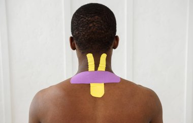 Boynunda kinesioteyp olan Amerikalı Afrikalı bir adam beyaz arka planda izole edilmiş, kopyalama alanı, yakın plan
