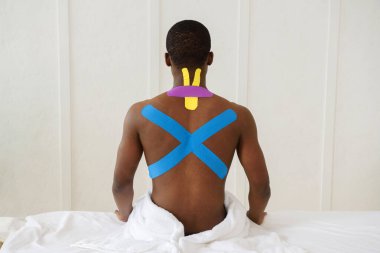 Boynunda ve sırtında Kinesioting olan Amerikalı Afrikalı bir adam beyaz arka planda izole edilmiş, kopyalama alanı, yakın plan