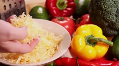 Sebze dolu bir masada rendelenmiş peynir.