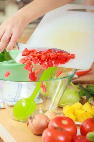Femme préparant salade de légumes tranchant poivron rouge — Photo