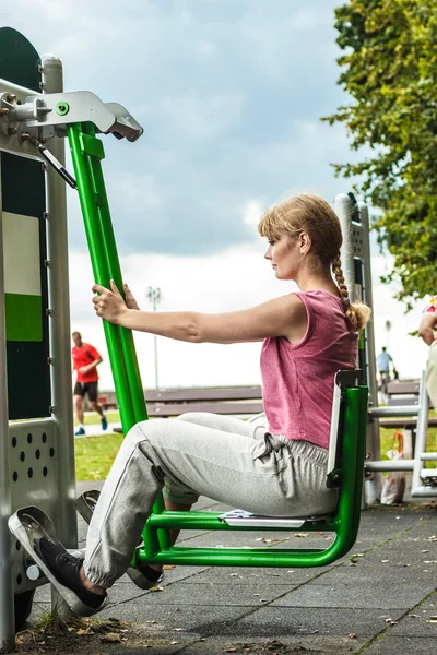 Mujer activa haciendo ejercicio en la prensa de piernas al aire libre . — Foto de Stock