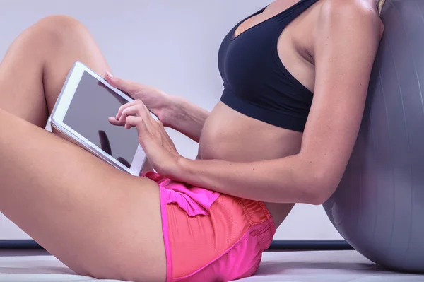 Fit woman sitting on floor with tablet pc — Stock Photo, Image