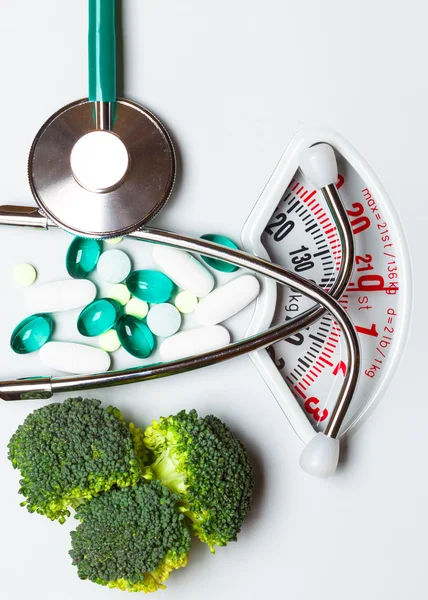 Broccoli stethoscope pills on weight scale. Dieting — Stock Photo, Image