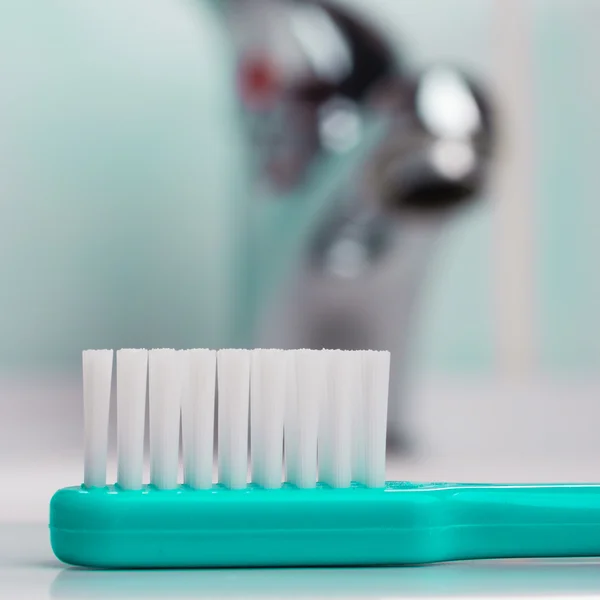 Cepillo de dientes verde en el baño en el fregadero — Foto de Stock