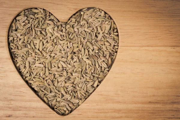 Rezene dereotu tohumu kalp şeklinde ahşap tahta üzerinde — Stok fotoğraf