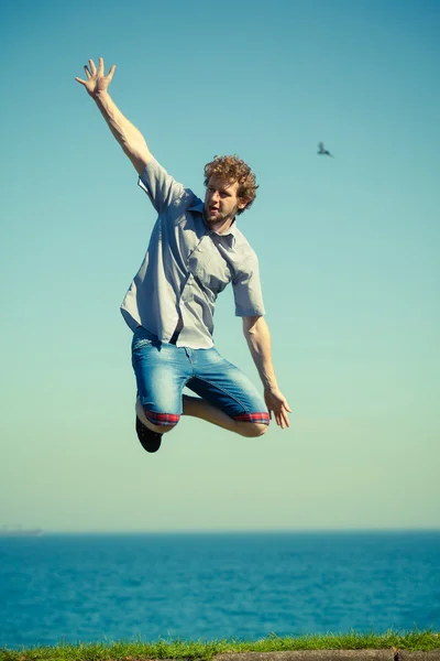 Carefree man jumping by sea ocean water. — Stock Photo, Image