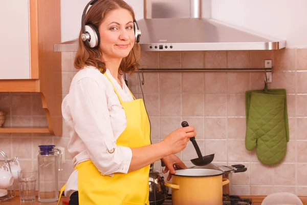 Dona de casa com fones de ouvido na cozinha — Fotografia de Stock