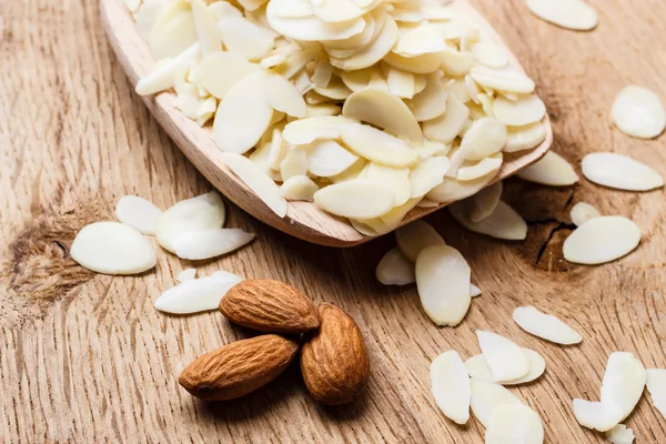 En rodajas y almendras crudas enteras sobre superficie de madera —  Fotos de Stock