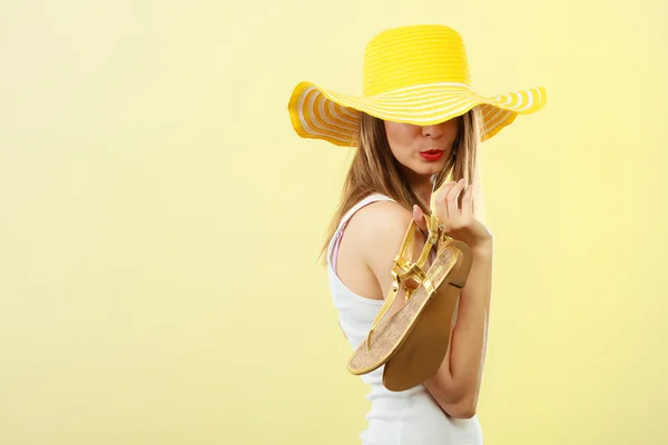 Mujer en gran sombrero de verano amarillo sostiene sandalias —  Fotos de Stock