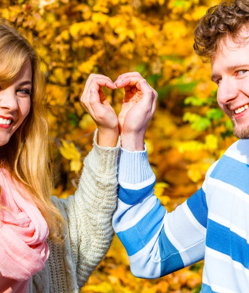 Giovani amanti nel parco autunnale fanno gesto del cuore . — Foto Stock