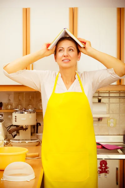 Femme au foyer drôle avec livre de cuisine sur la tête — Photo