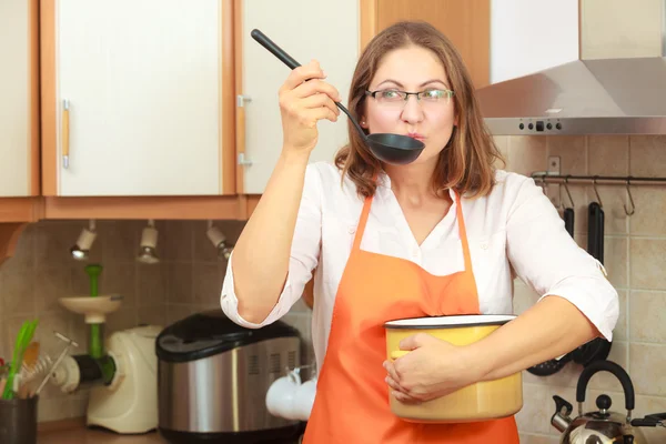 Mujer con cucharón y olla en la cocina — Foto de Stock