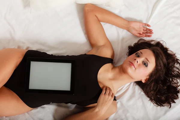 Sexy lazy girl lying with tablet touchpad on bed — Stock Photo, Image