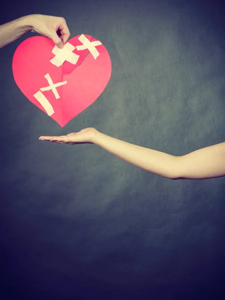 Woman and man hands holds broken heart. — Stock Photo, Image