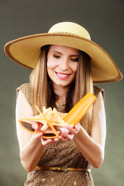 Kadın güneş gözlüğü ve güneş koruyucu losyon tutar