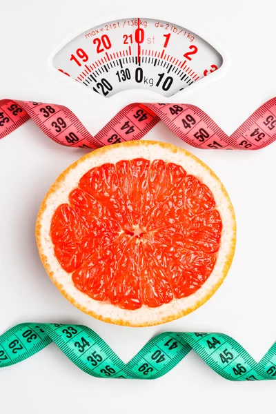 Grapefruit with measuring tape on weight scale. Dieting — Stock Photo, Image