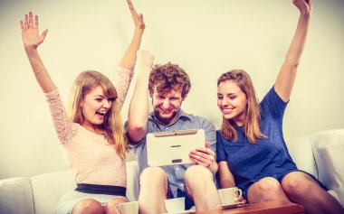 Evde tablet ile başarılı mutlu arkadaşlar.