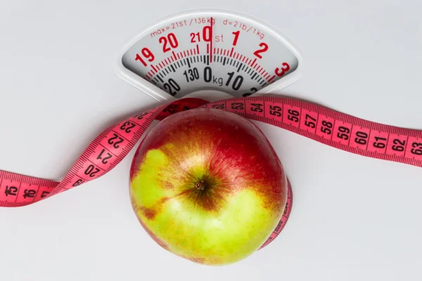 Apple with measuring tape on weight scale. Dieting — Stock Photo, Image