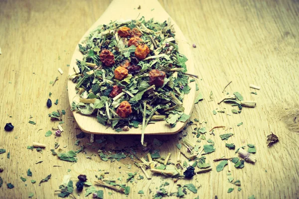 Pile of dry herb leaves and fruits on wooden spoon — Stock Photo, Image