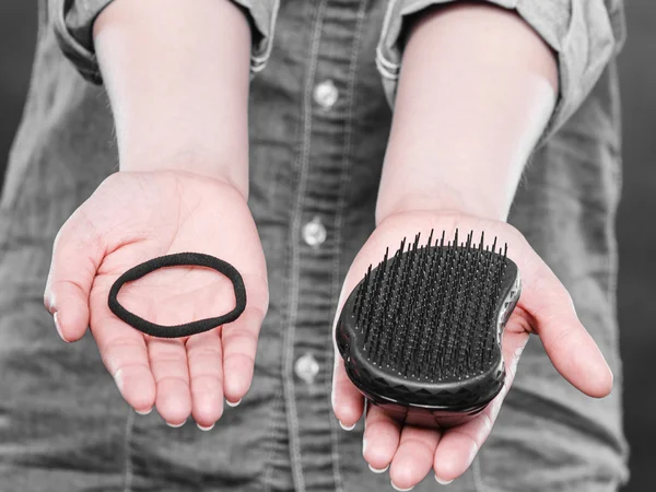 Vrouwelijke handen met kam en elastisch haar. — Stockfoto