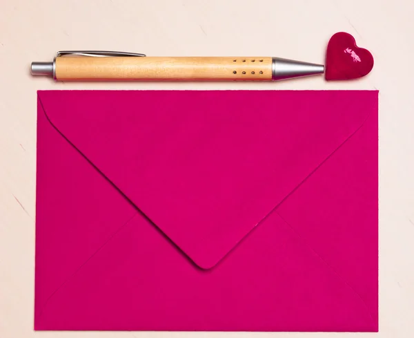 Розовый конверт сердце и ручка на столе — стоковое фото