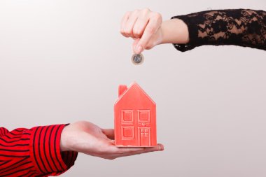 İnsanlar elleriyle küçük ev ve gümüş sikke.