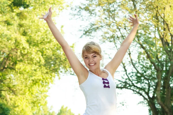 Mulher sorrindo alegre com os braços para cima ao ar livre — Fotografia de Stock