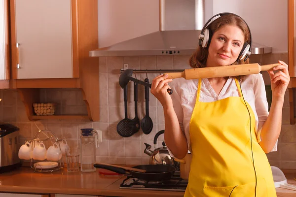 Dona de casa com fones de ouvido na cozinha — Fotografia de Stock