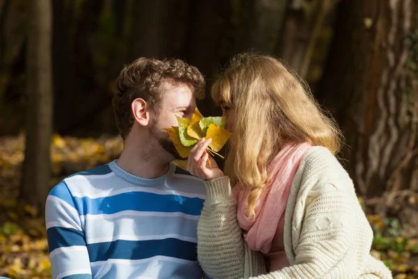 Casal beijando no outono parque escondido atrás de folhas — Fotografia de Stock