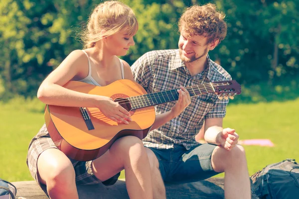 Jovem casal camping tocando guitarra ao ar livre — Fotografia de Stock