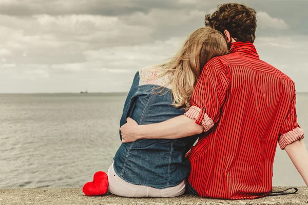 Пара сидящих обнимающихся на берегу моря — стоковое фото