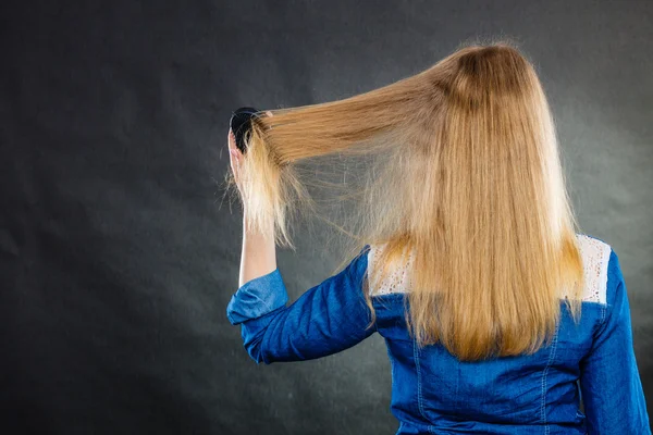 Blonde woman combing her hair.