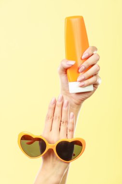 Kadın güneş gözlüğü güneş losyonu tutar.
