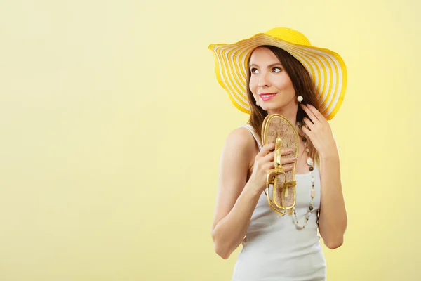 Woman in big yellow summer hat holds sandals — Stock Photo, Image