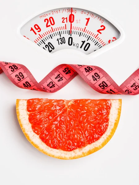 Grapefruit with measuring tape on weight scale. Dieting — Stock Photo, Image