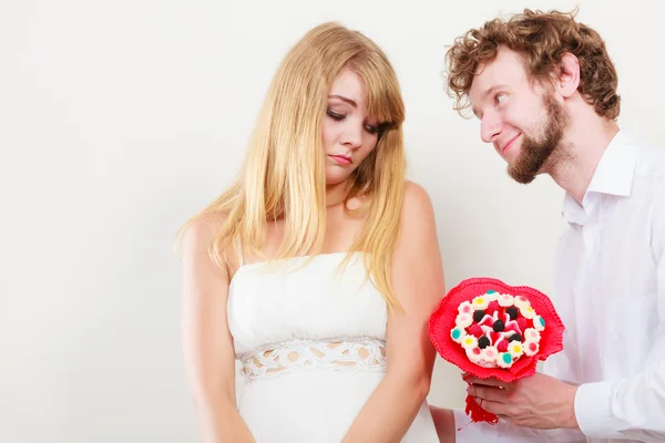 Geven van snoep bos bloemen aan triest vrouw man. — Stockfoto