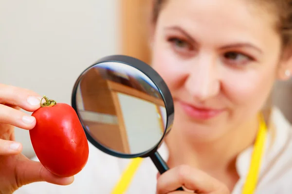 Женщина осматривает помидор увеличительным стеклом . — стоковое фото