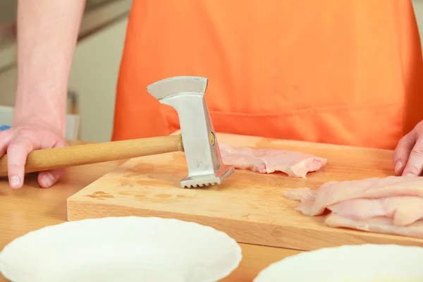 Homme battant la viande de poulet sur une planche de bois — Photo