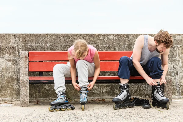 Människor vänner att sätta på rullskridskor utomhus. — Stockfoto