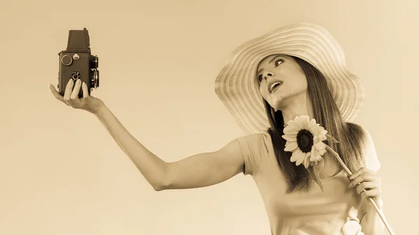 Vrouw houdt zonnebloem en oude camera — Stockfoto