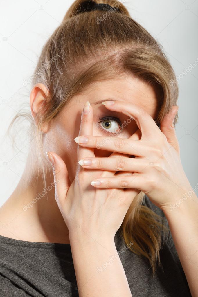 Close up of a young scared and frightened woman, covering herself