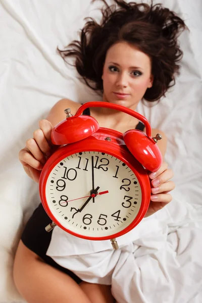 Kırmızı alarm clock yatakta yatan seksi tembel kız — Stok fotoğraf