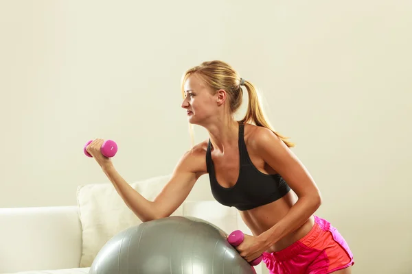 Mujer con pelota de gimnasio y mancuerna haciendo ejercicio — Foto de Stock