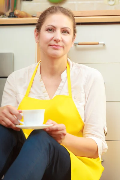 Zralá žena s šálkem kávy v kuchyni. — Stock fotografie