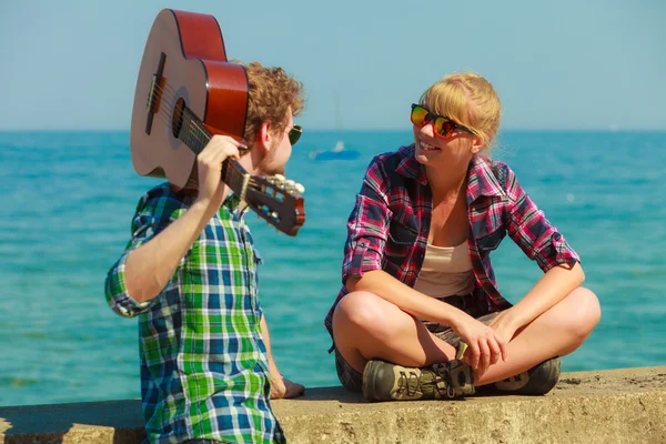 Joven tocando la guitarra a su novia junto al mar — Foto de Stock